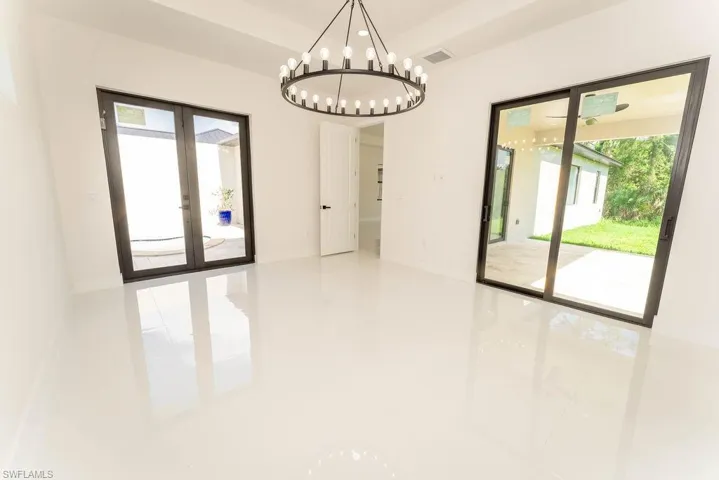 Unfurnished dining area with french doors, plenty of natural light, and a chandelier