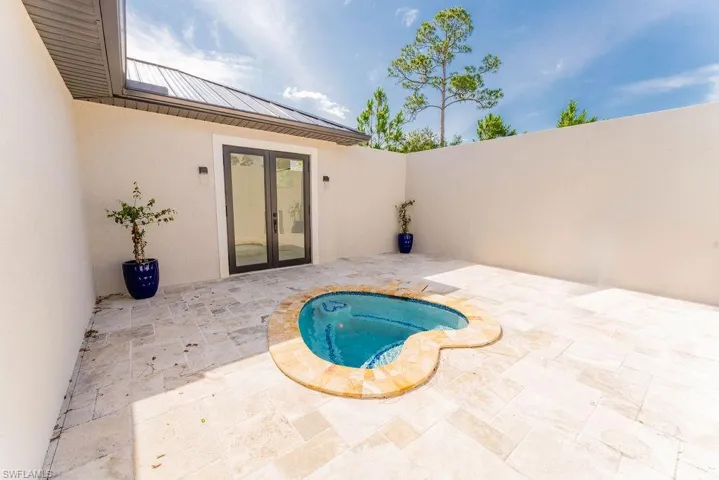 View of pool with french doors, a patio, and an in-ground hot tub