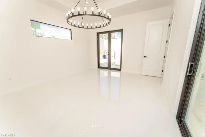 Unfurnished room featuring french doors and a chandelier
