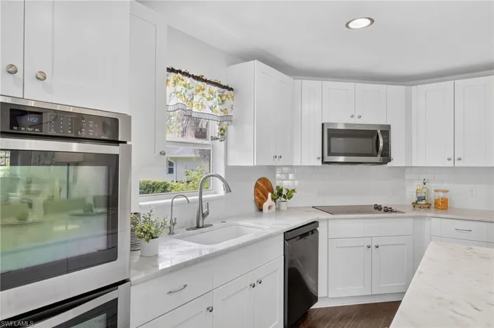Beautifully updated kitchen with new SS appliances, spacious island with marble countertops, tile backsplash, large deep kitchen sink, white shaker cabinets,  a large pantry. and access to the backyard