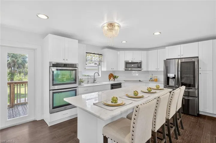 Beautifully updated kitchen with new SS appliances, spacious island with marble countertops, tile backsplash, large deep kitchen sink, white shaker cabinets,  a large pantry. and access to the backyard