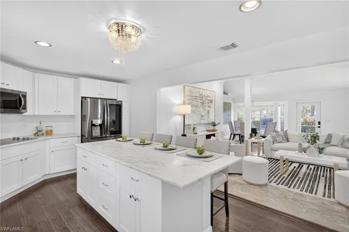 Beautifully updated kitchen with new SS appliances, spacious island with marble countertops, tile backsplash, large deep kitchen sink, white shaker cabinets,  a large pantry. and access to the backyard