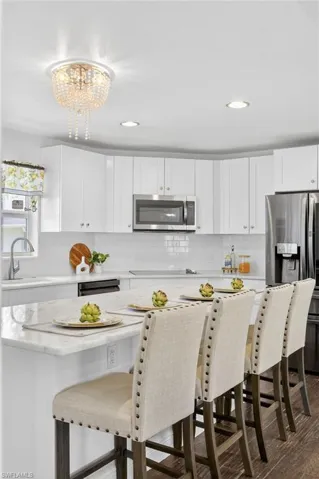 Beautifully updated kitchen with new SS appliances, spacious island with marble countertops, tile backsplash, large deep kitchen sink, white shaker cabinets,  a large pantry. and access to the backyard