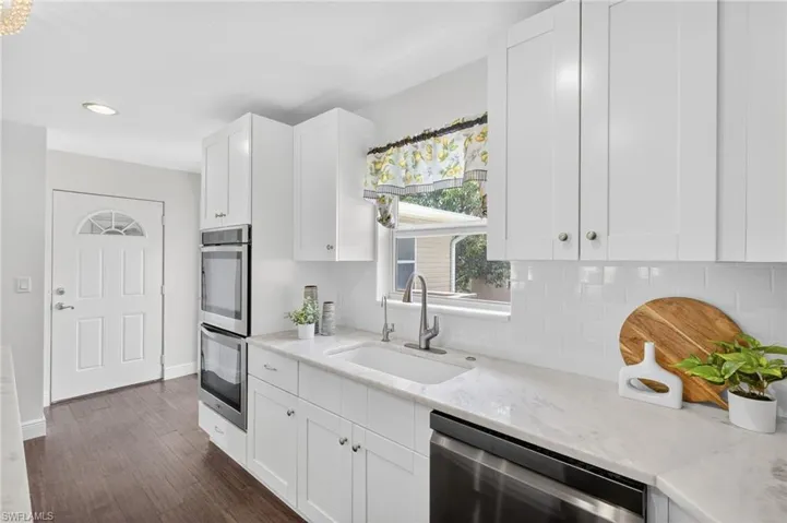 Beautifully updated kitchen with new SS appliances, spacious island with marble countertops, tile backsplash, large deep kitchen sink, white shaker cabinets,  a large pantry. and access to the backyard