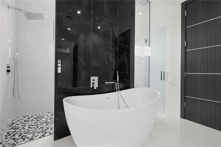 Bathroom with a marble finish shower, marble tiled floors, and a soaking tub