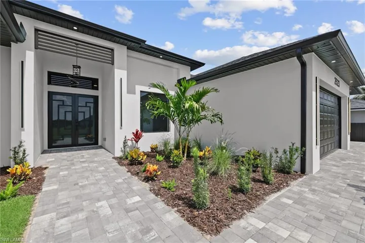 Entrance to property with stucco siding, an attached garage, and driveway