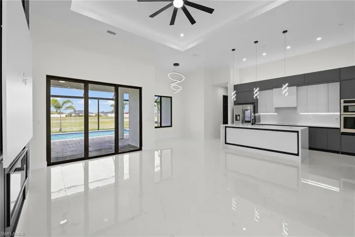 Kitchen with modern cabinets, light marble finish floors, recessed lighting, stainless steel fridge, and a high ceiling