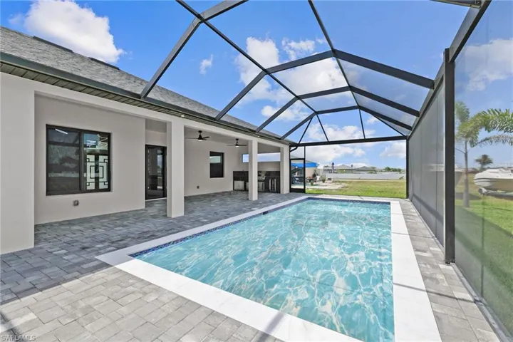 Outdoor pool featuring a ceiling fan, a patio area, and glass enclosure