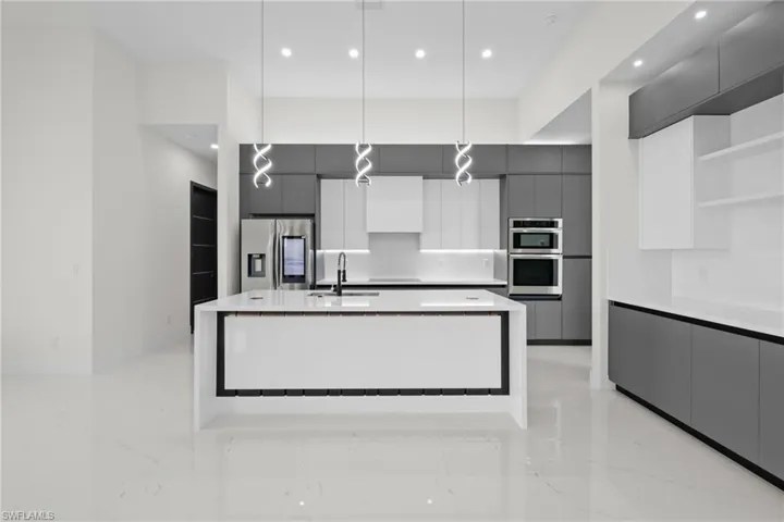 Kitchen with appliances with stainless steel finishes, modern cabinets, light marble finish floors, open shelves, and recessed lighting