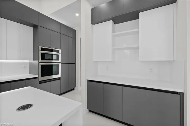 Kitchen with open shelves, modern cabinets, light countertops, double oven, and recessed lighting