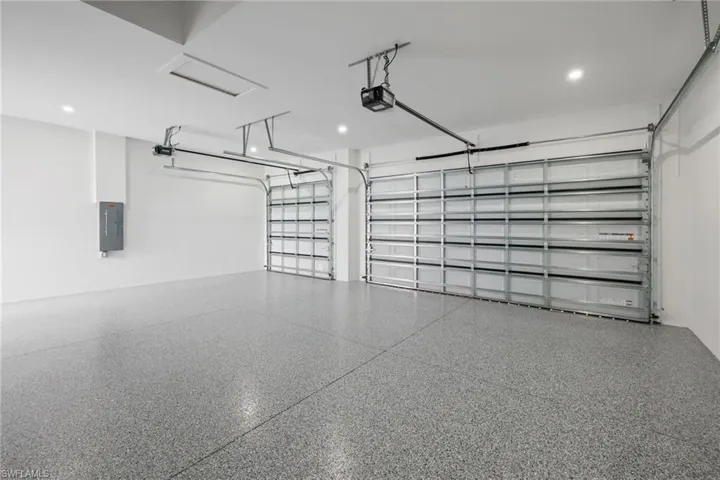 Garage with electric panel, a garage door opener, and recessed lighting