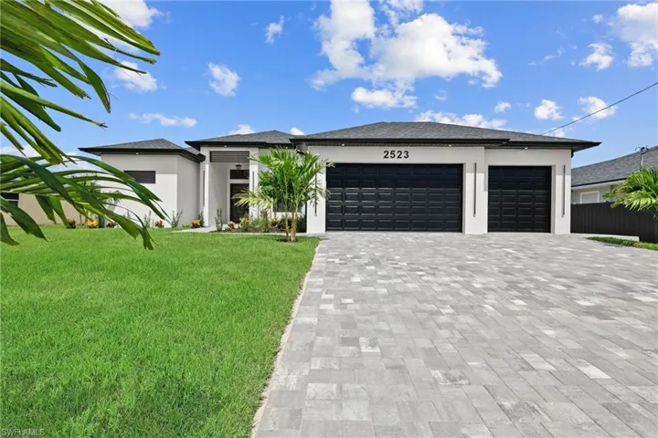 Prairie-style home with a garage, a front lawn, decorative driveway, and stucco siding