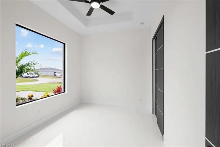Unfurnished room featuring a ceiling fan, a raised ceiling, and a smoke detector