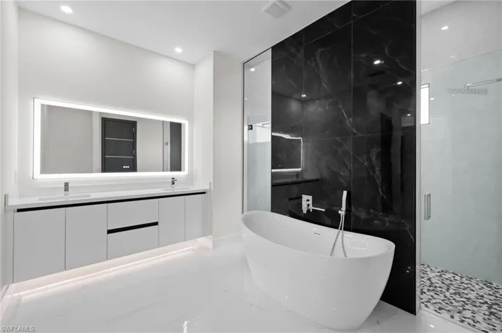Bathroom featuring marble tiled flooring, a soaking tub, a shower stall, double vanity, and recessed lighting