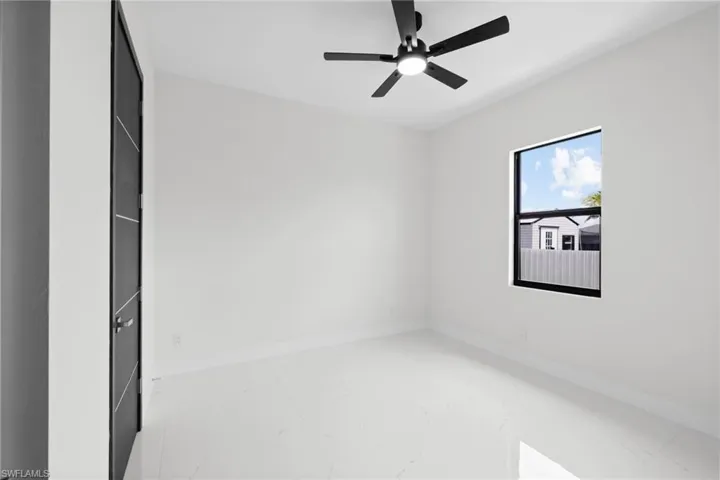Spare room with marble finish flooring, baseboards, and a ceiling fan