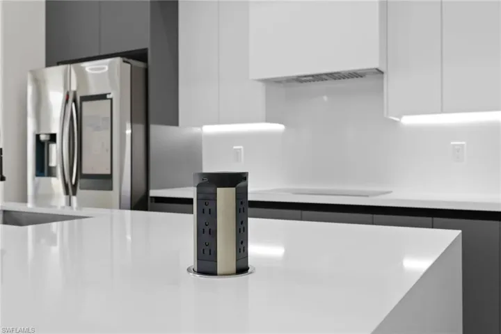 Kitchen view of stainless steel refrigerator with ice dispenser, modern cabinets, light countertops, and white cabinets