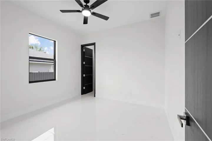 Unfurnished room featuring a ceiling fan, marble finish floors, and baseboards