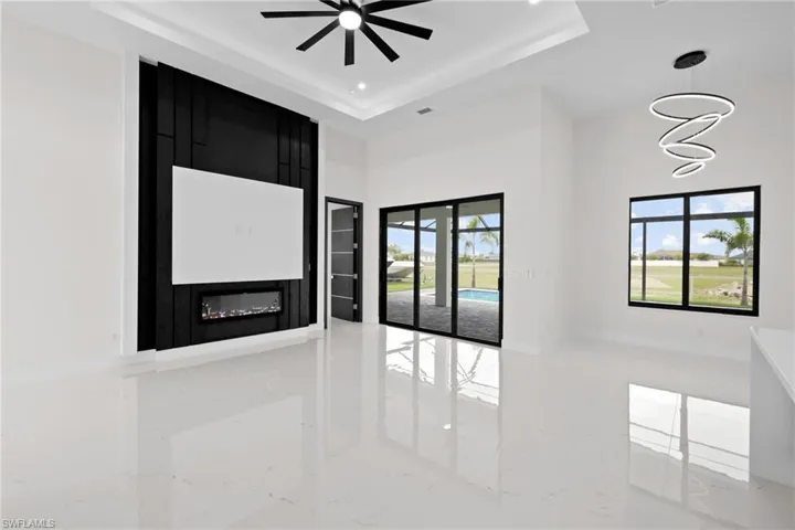 Empty room with light marble finish floors, a raised ceiling, a high ceiling, ceiling fan, and recessed lighting