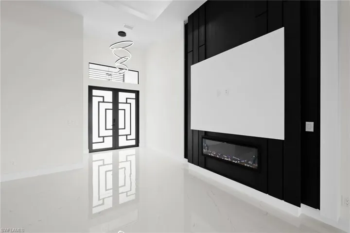 Detailed view of a chandelier, a glass covered fireplace, and baseboards