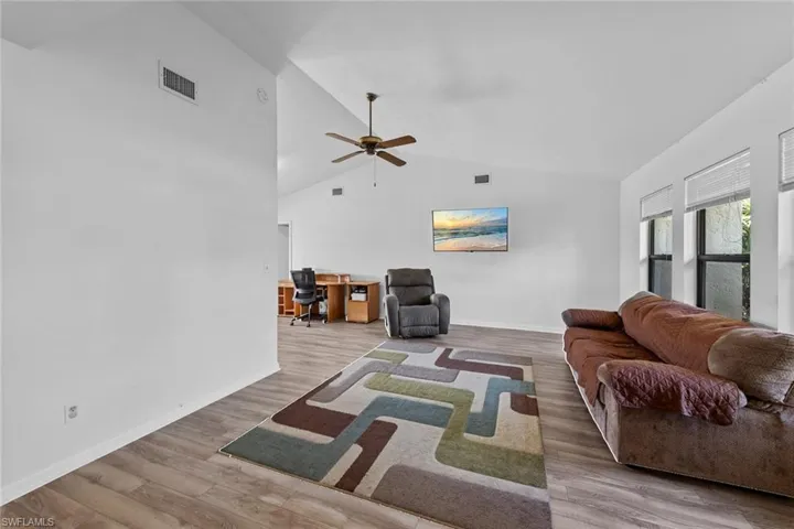 Living room with ceiling fan, wood-type flooring, and lofted ceiling