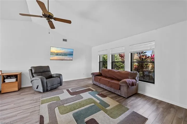 Living room with wood-type flooring, ceiling fan, and lofted ceiling
