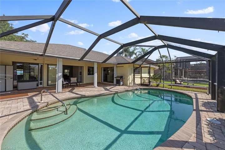View of swimming pool with lanai enclosure, a patio, and grilling area
