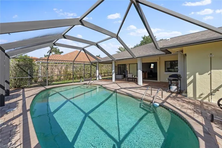 View of pool with a grill, a patio, and lanai enclosure