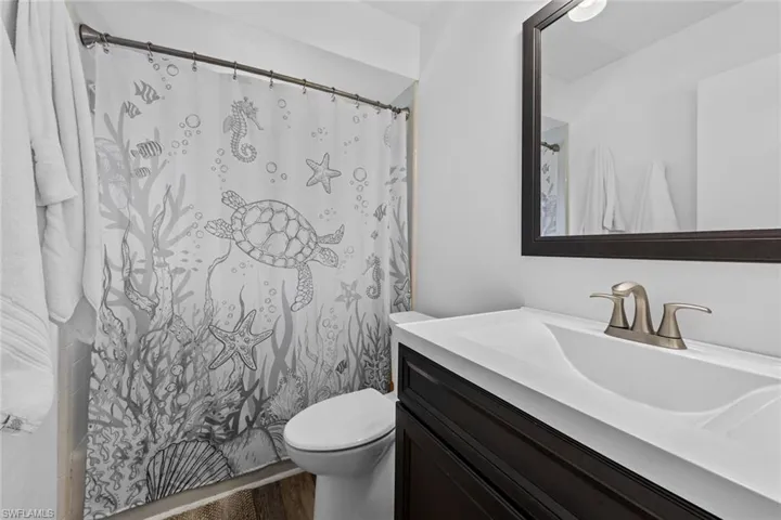 Guest Bathroom featuring hardwood / wood-style floors, vanity, toilet, and a shower with curtain