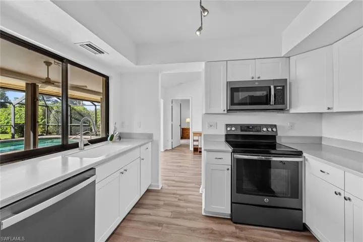 Kitchen with white cabinetry, sink, light hardwood / wood-style flooring, and appliances with stainless steel finishes