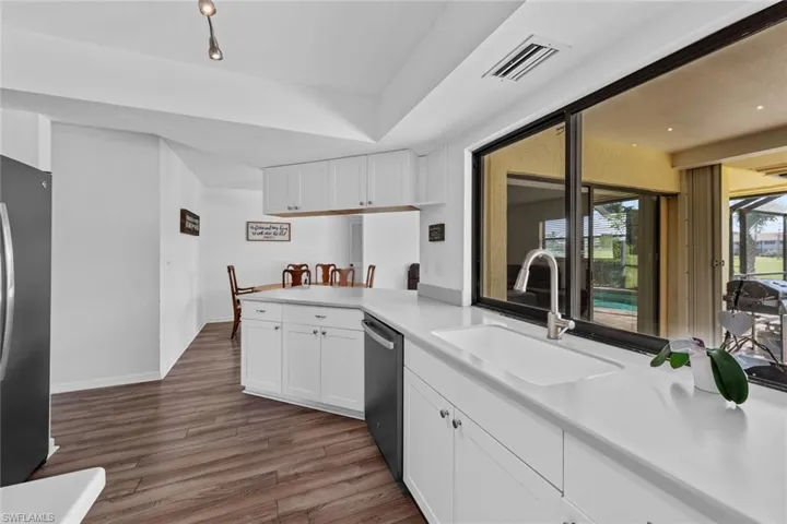 Kitchen with dark wood-type flooring, sink, appliances with stainless steel finishes, white cabinetry, and kitchen peninsula