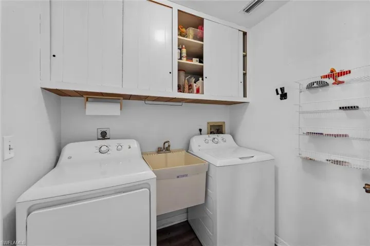 Laundry room with hardwood / wood-style floors, cabinets, separate washer and dryer, and sink