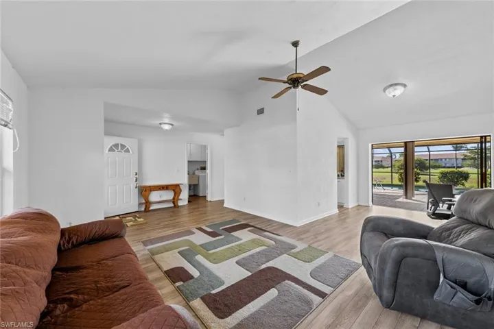 Living room featuring ceiling fan, lofted ceiling, and light hardwood / wood-style flooring
