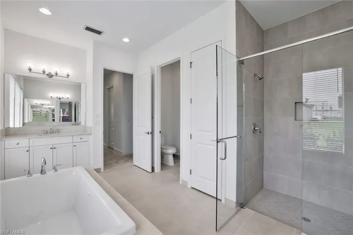 Master bathroom featuring separate shower and tub, toilet, tile floors, and large vanity