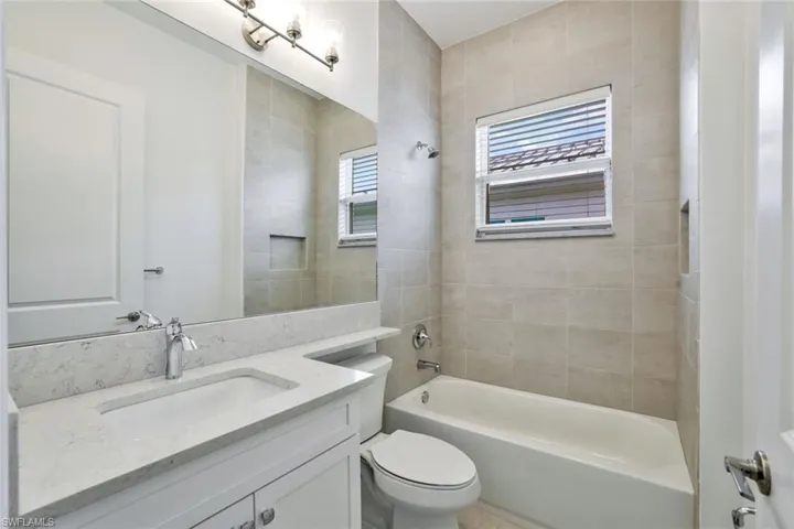 Full bathroom featuring tiled shower / bath, vanity, and toilet
