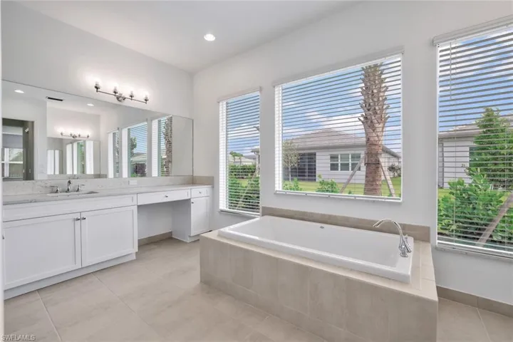 Master Bathroom featuring tile floors, a relaxing tiled bath, and vanity