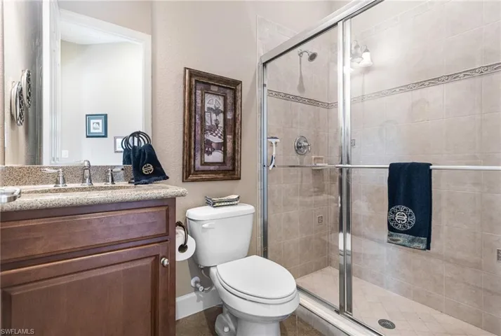 Bathroom with vanity, a shower stall, toilet, and baseboards