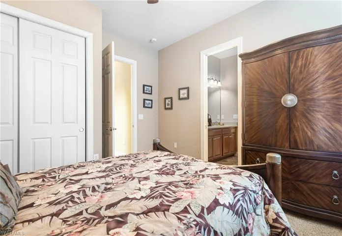 Carpeted bedroom with a closet, connected bathroom, and a ceiling fan