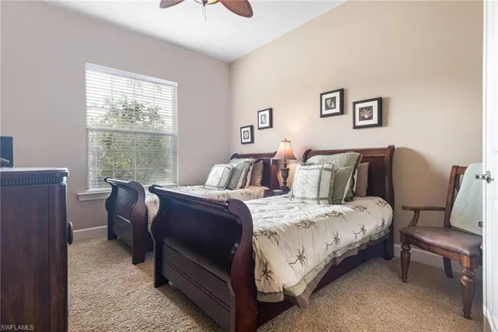 Bedroom with light carpet, a ceiling fan, and baseboards