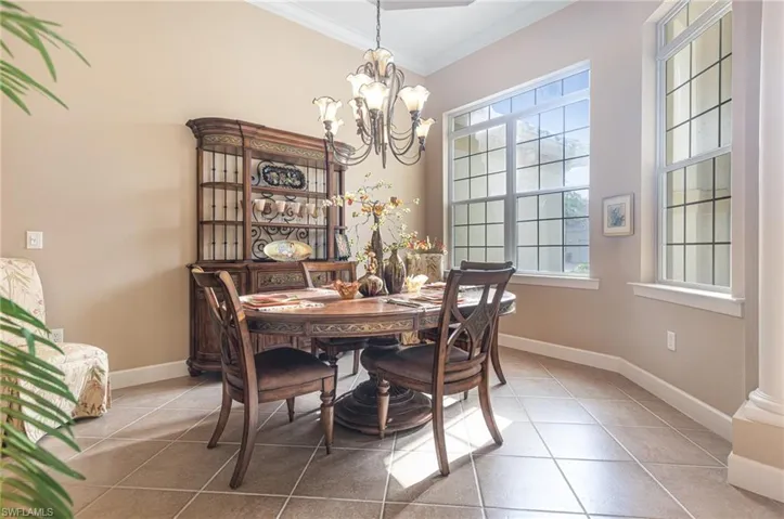 Dining area featuring baseboards, a chandelier, tile patterned flooring, and ornamental molding