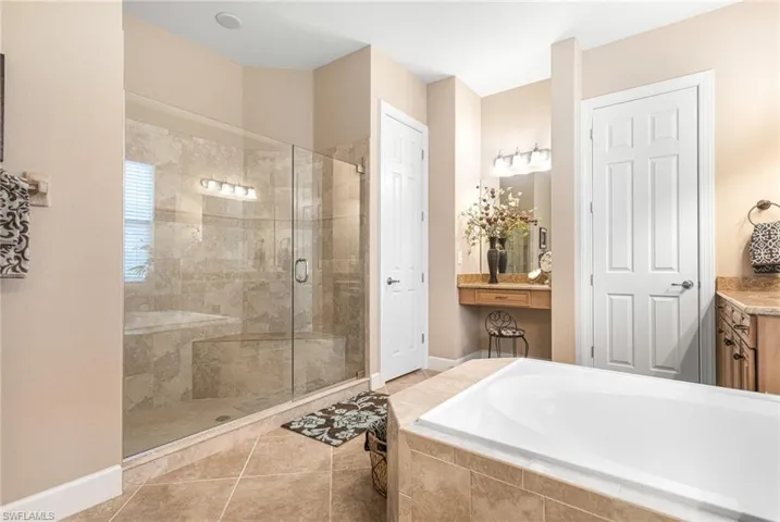 Full bath featuring vanity, a garden tub, baseboards, and a stall shower
