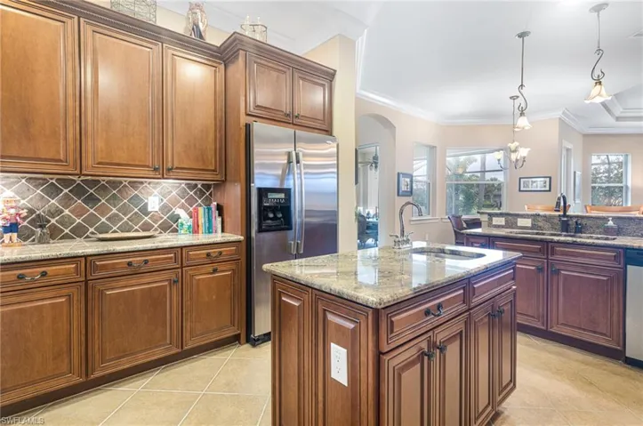 Kitchen featuring arched walkways, stainless steel appliances, crown molding, and a sink