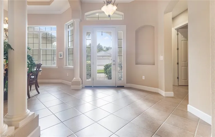 Entrance foyer featuring light tile patterned floors, baseboards, and ornate columns