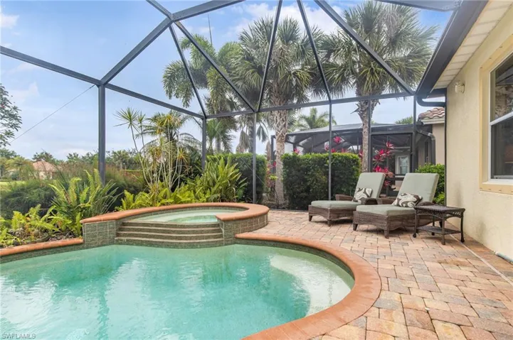 View of swimming pool featuring a lanai, a pool with connected hot tub, and a patio