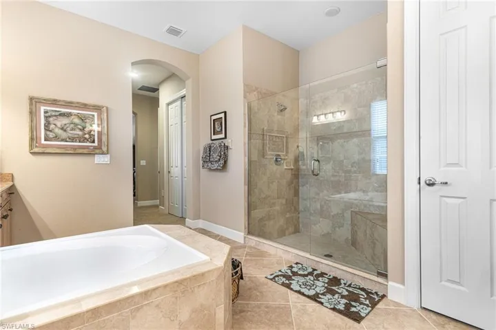 Full bath featuring tile patterned floors, visible vents, a garden tub, a stall shower, and vanity