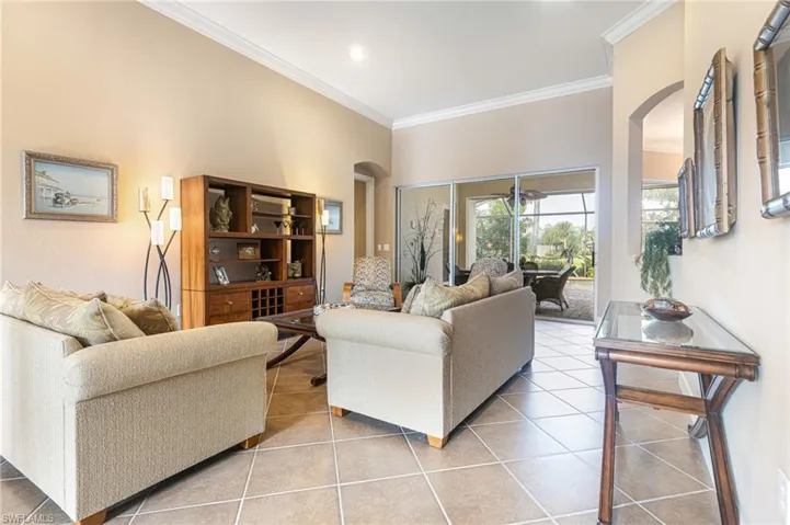 Living room with arched walkways, tile patterned floors, and ornamental molding