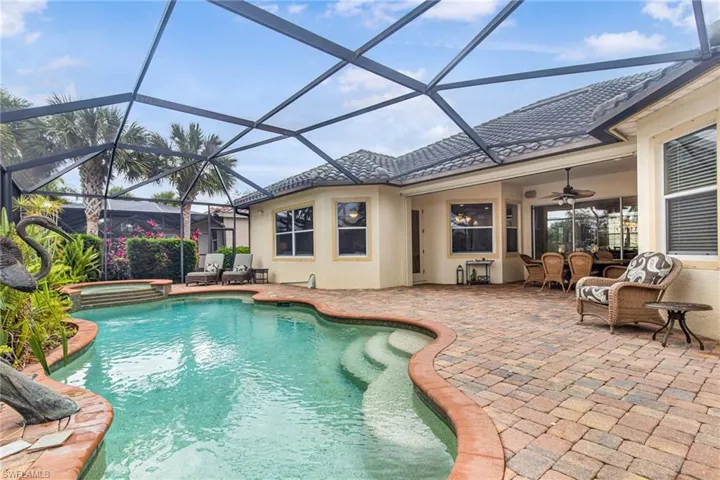View of swimming pool featuring glass enclosure, a pool with connected hot tub, ceiling fan, and a patio area