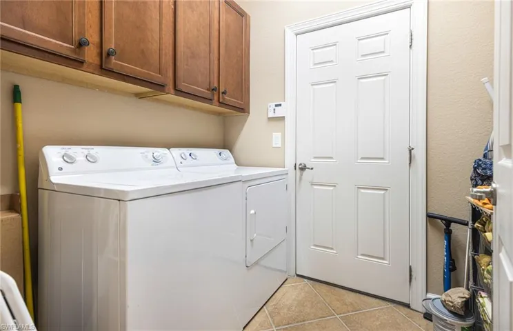 Laundry room with washer and dryer, cabinet space, and light tile patterned flooring