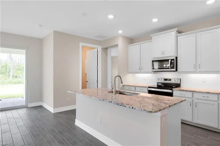 Kitchen with appliances with stainless steel finishes, a center island with sink, decorative backsplash, and sink