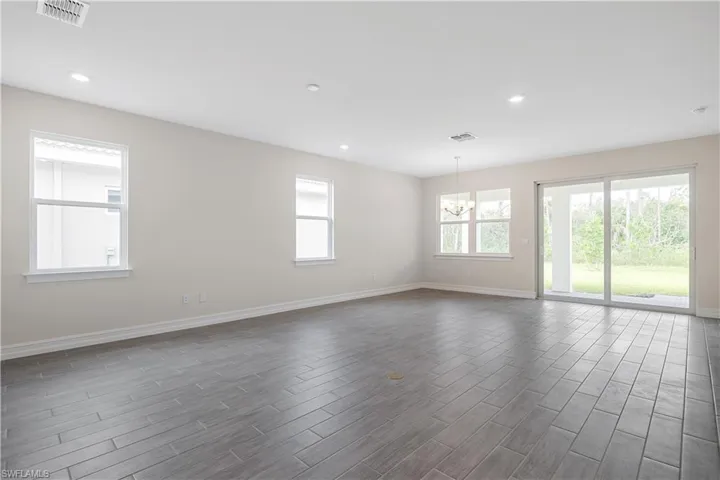 Empty room featuring a wealth of natural light, dark wood-type flooring, and a notable chandelier