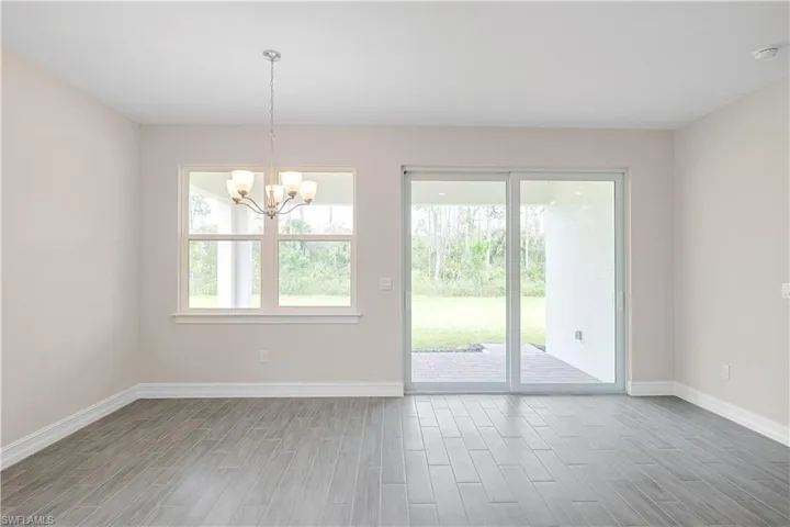 Spare room with an inviting chandelier and wood-type flooring